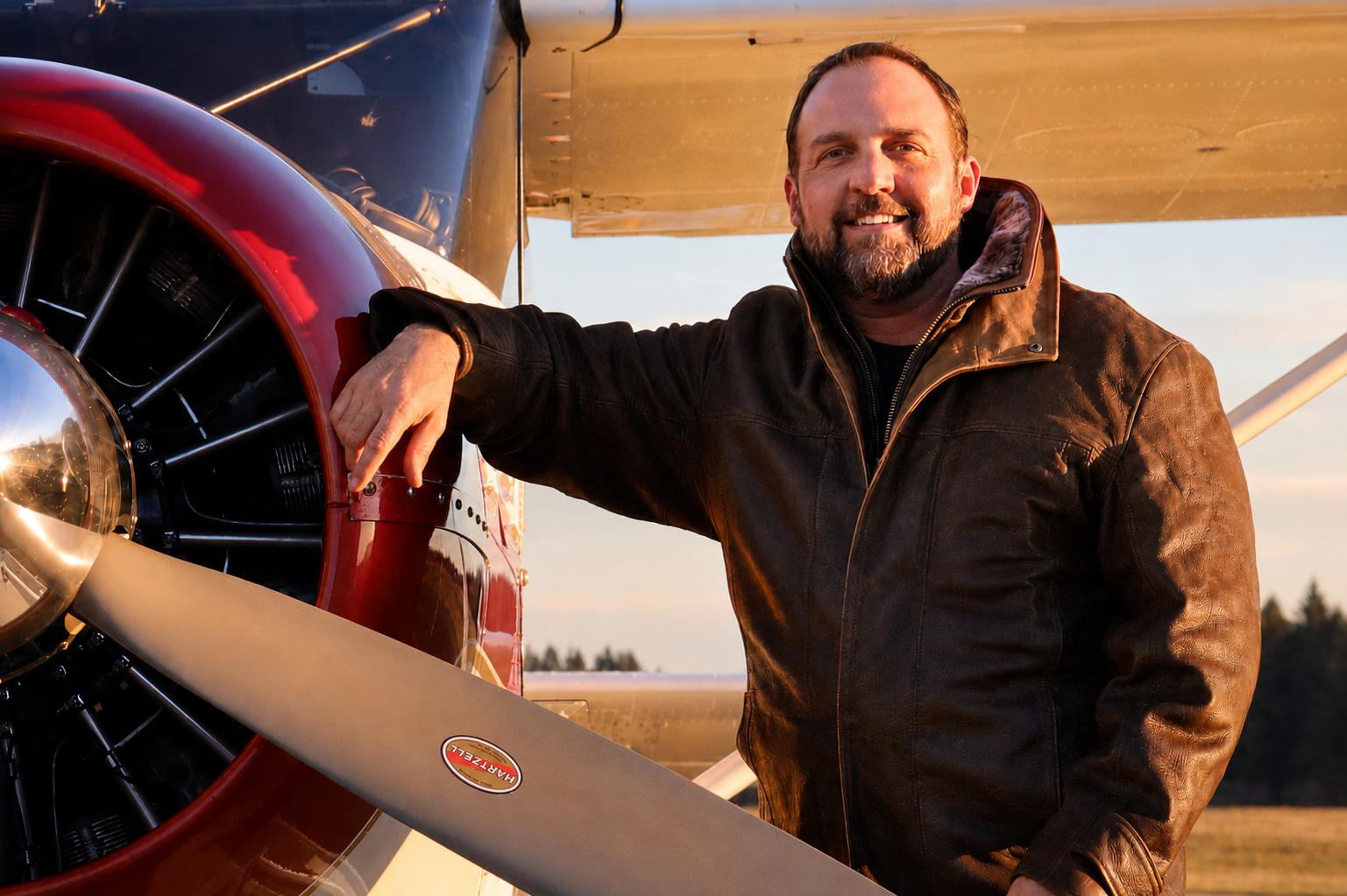 Vernon Bonfield, founder of WHIA, leaning on the propeller cowling of a vintage airplane